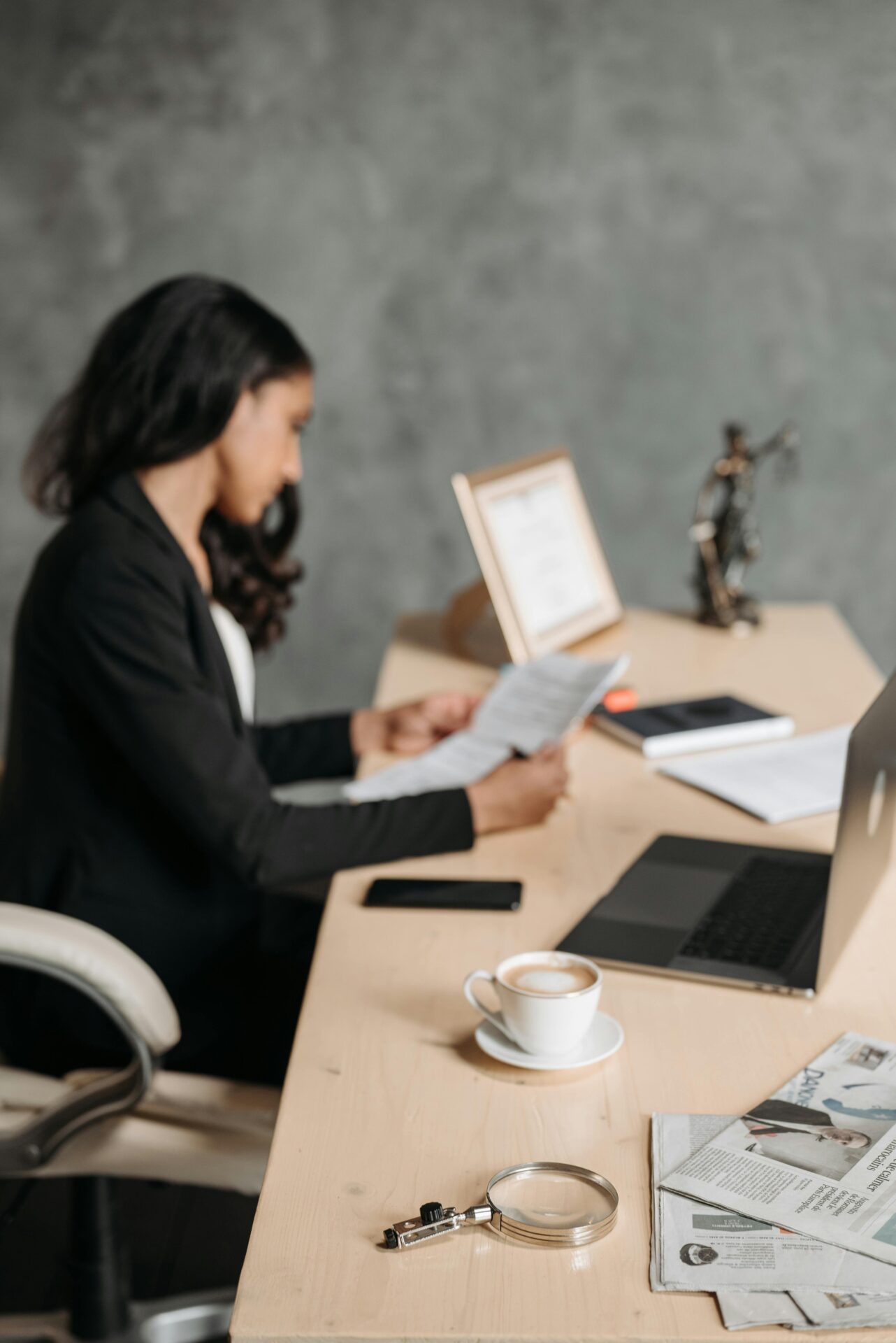 Professional translator reviewing a document at her desk with a coffee and laptop